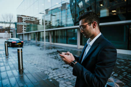 Mixed race businessman chatting on smartphone walking to work in office buildingの写真素材