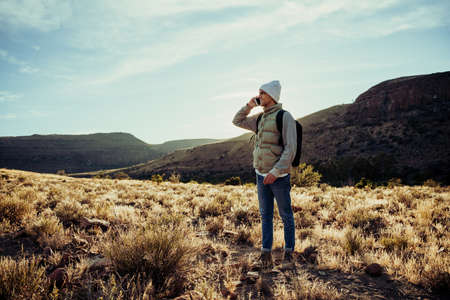 Caucasian male teen feeling lost calling girlfriend looking for directions while hiking in mountain