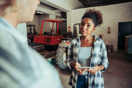 Mixed race female chatting to caucasian male while holding digital tablet