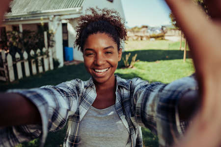 Mixed race female taking selfie with cellular device standing outdoors on farm