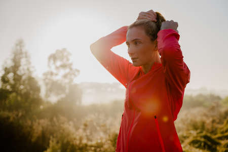 Beautiful young woman preparing for athletic run in the park, tiring up hear to begin exercisingの写真素材