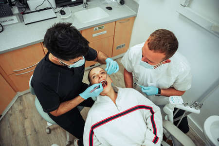 Caucasian female patient lying on doctors bed while male nurse operatesの写真素材