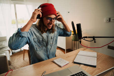 Caucasian male freelance worker recording podcast with microphone for internet subscribersの写真素材