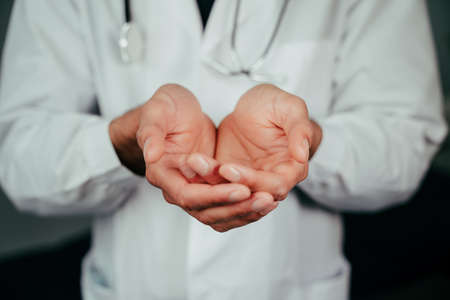 Caucasian male doctor standing in office with hands openの写真素材