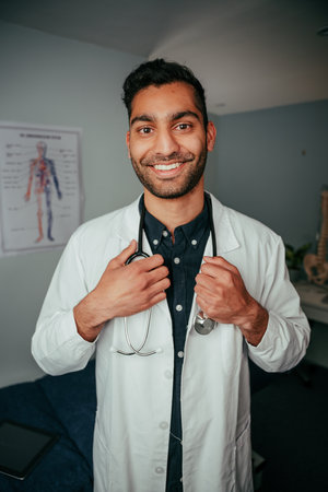 Mixed race smiling male doctor standing in clinic