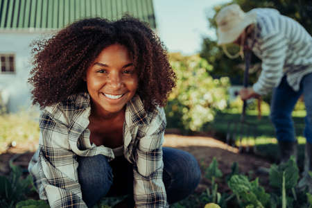 Beautiful smiling female farmer working in vegetable garden organising produce feeling activeの写真素材
