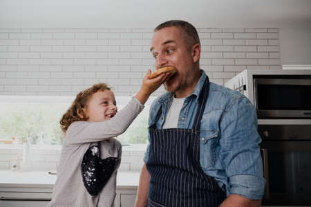 Father and daughter cooking in the kitchen having fun together on fathers dayの写真素材