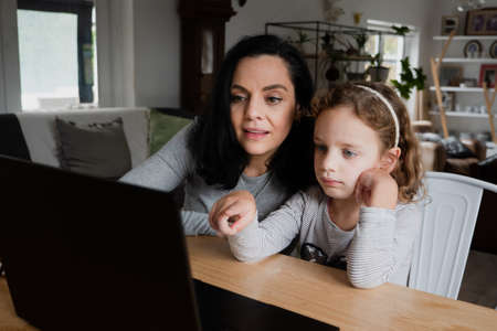 Mother teaching young daughter at home on the computer with e-learning coursesの写真素材
