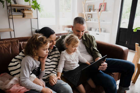 Happy family watching movies off laptop sitting on sofa in comfy lounge.の写真素材