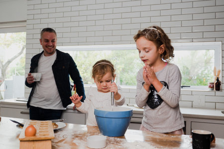 Father and two daughters baking in kitchen together