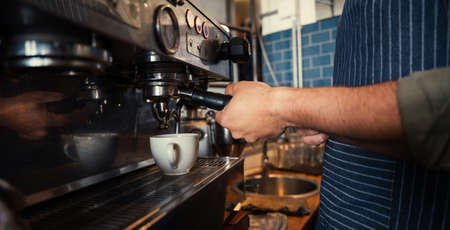 Male barista brewing coffee for customers in funky restaurantの写真素材