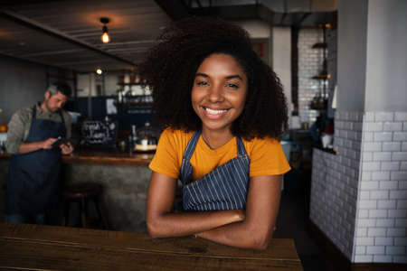 Beautiful African American woman smiling while cross elbowed in stylish coffee shop.の写真素材