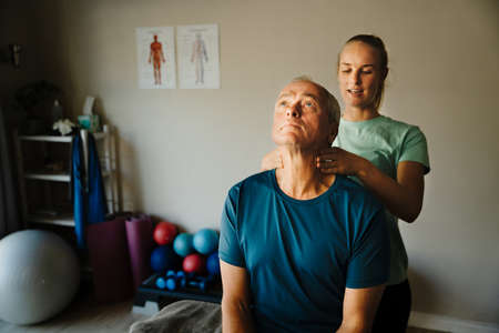 female physiotherapist performs neck test for elderly maleの写真素材