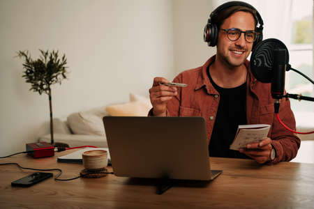 Caucasian male freelance podcaster chatting to listeners while writing notes abut important topics