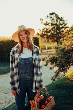 Caucasian female farmer smiling after successfully picking fresh vegetables from gardenの写真素材