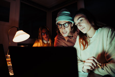 Caucasian students working late at night in home office typing on laptop finishing assignments meeting deadlinesの写真素材