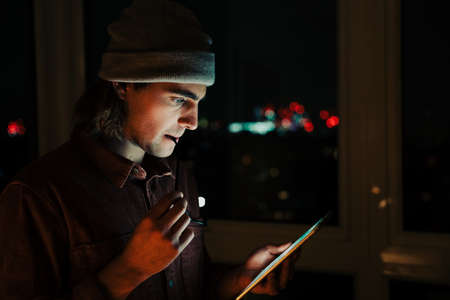 Caucasian business man checking emails on digital tablet working late at night in apartmentの写真素材