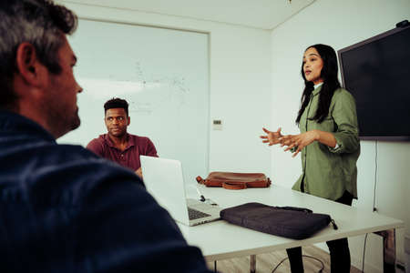 Female executive presenting project to manager and clients standing nervously in board room