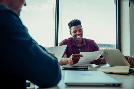 Male business man laughing with team of colleagues discussing points to improve businessの写真素材