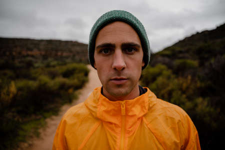 Portrait of concentrating fit young male athlete resting after tough mountain run on gravel roadの写真素材