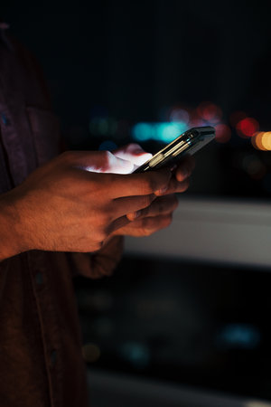 Close up of caucasian business man typing on cellular device working late at night in apartment