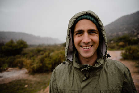 Portrait handsome young male athlete smiling hood on head for protection from rain while running on...