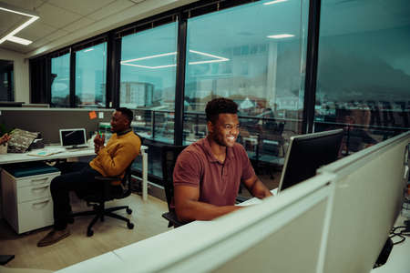 mixed race male designer working on marketing report typing on desktop computer in office