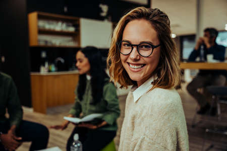 Close up of smiling caucasian business woman sitting contently in office lounge chatting with...