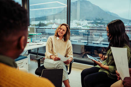 Beautiful smiling caucasian business woman laughing with colleagues in office before lunch break