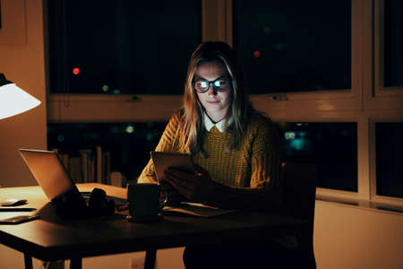 Caucasian business woman working at office desk busy with business report reading emails on digital...