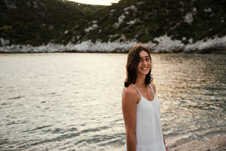 Beautiful caucasian female walking by the ocean smiling enjoying honeymoonの写真素材