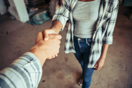 Close up mixed race couple hand shaking after long day of workの写真素材