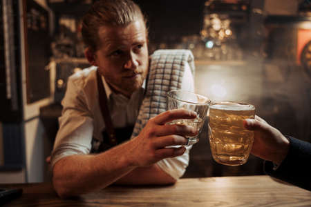 caucasian male bartender enjoying drink with customer sitting at the barの写真素材