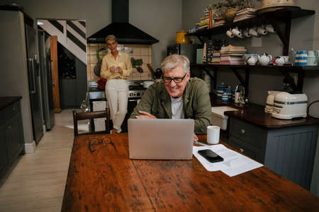 smiling elderly male sitting at kitchen table