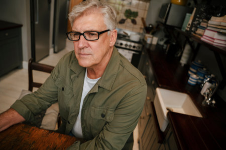 caucasian elderly male working in kitchen thinking to himself