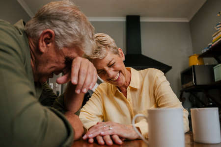 Happy caucasian senior couple laughing together at morning teaの写真素材