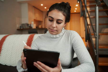 Caucasian female student working from home sitting on sofaの写真素材