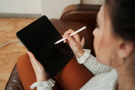 Caucasian female student working from home drawing on digital tabletの写真素材
