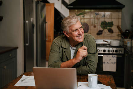 Caucasian senior male working from home smiling to himselfの写真素材