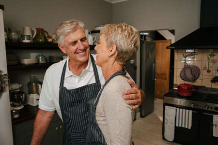 romantic affectionate mature couple hugging in kitchenの写真素材