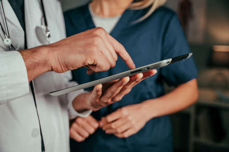 Close up male doctor typing on digital tabletの写真素材