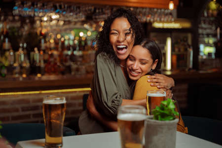 Female friends hugging each other in restaurantの写真素材