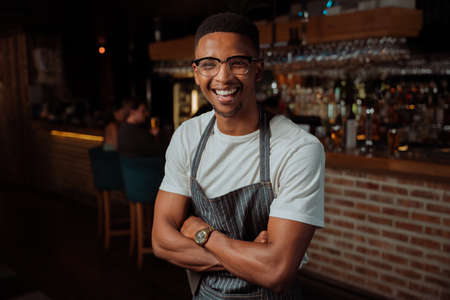 Portrait of Male waiter laughing while at work with apronの写真素材