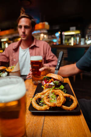 friends out for dinner eating burger and onion ringsの写真素材