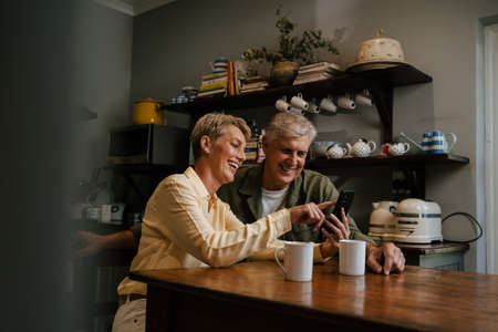 Caucasian senior couple drinking coffee in kitchenの写真素材