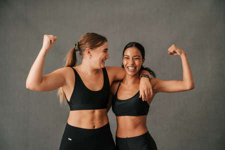 Two girlfriends showing there toned arm musclesの写真素材