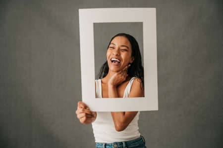 Laughing smiling close up of multiethnic female holding a frameの写真素材