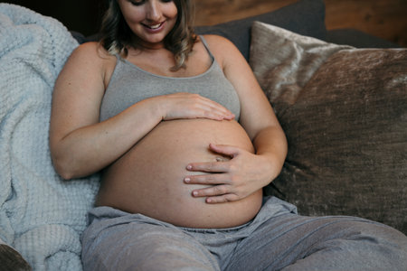 Mother to be tenderly looking down at her belly and smiling