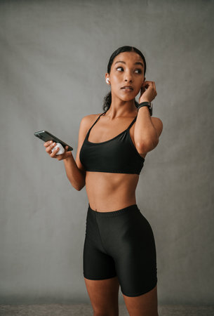Multiethnic female holding her cellphone and ear pod containerの写真素材