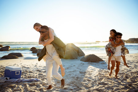 Guys Carrying Women on Their Back At The Beachの写真素材